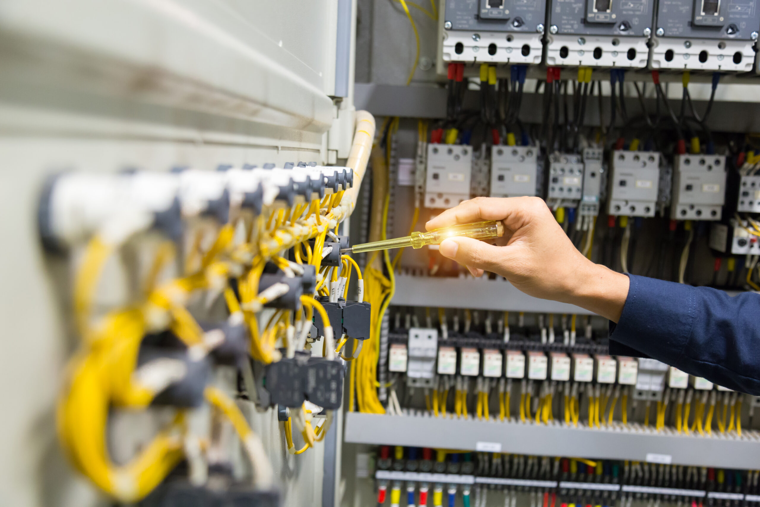 electricians hands testing current electric control panel scaled